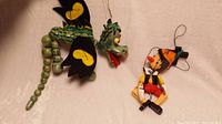 Two vintage wooden marionettes laid out on flat surface showing full body of dragon and Pinocchio puppets.