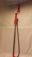 Front view of a large Ridgid drain snake featuring a red handle and long coil cable.