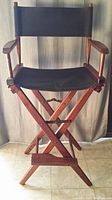 Full front view of the tall folding director's chair with black canvas and wood frame