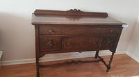Front view of antique tiger oak buffet showing drawers, detailed wood grain, and carved backboard.