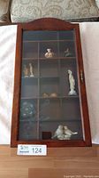 Closed view of wooden display case with etched glass door showing various small figurines inside compartments