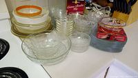 Multiple sizes of clear glass plates and bowls, Mikasa red sweet dish, and Creme Brulee kit on counter