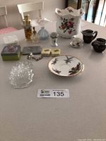 Full lot of vintage miscellaneous decor items on table, showing perfume bottles, Royal Stafford bone china plant pot, cream and sugar bowl, and glass and brass decorative pieces.