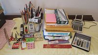 Full view of the lot showing the majority of office supplies including pens, scissors, stapler, papers, envelopes, tape, and calculators.
