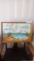 Full view of the original oil painting by Tom Brown Wilson showing a coastal scene with sand dunes, ocean, and sky, framed in a gold frame.