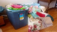 Photo of blue plastic bin and baskets filled with assorted folded sewing fabric including floral and solid colors