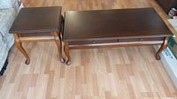 Photo showing the hardwood coffee table and end table set with cabriole legs and dark wood grain tops, on a light wood floor.