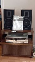 Shows the stereo system with the speakers and manual on top of the main cabinet, the speakers have Toshiba logos and black woodgrain finish.