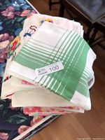 Stack of folded tablecloths showing a green and white striped pattern on top and other fabric colors underneath.