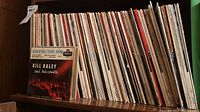 Shelf containing approximately 50 assorted 7” extended play records in sleeves