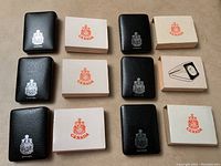 Photo of all six black presentation cases with white outer boxes bearing the Canada crest.