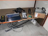 The full lot shown on a wooden shelf including the inverters, charger, control unit, and additional items with cables.
