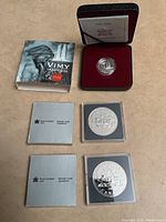 Overview of two 1981 silver dollar coins in original cases and Vimy 5 cent silver coin in red velvet display box with booklet.