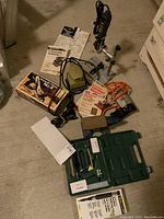 Photo of all power and hand tools including Dremel MultiPro tool on drill press, Black & Decker drill and sander, Mastercraft plane in box, two hot glue guns, cordless soldering iron, sanding papers and manuals.