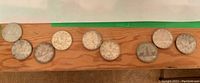 Row of nine circulated Canadian silver dollar coins on wood surface