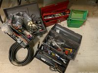 Photo showing three tool boxes with various hand tools and accessories including wires, hooks, torque wrench, and gas hose