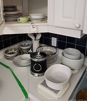 Wide shot showing assorted dishware on countertop including casserole dishes, ice bucket, ceramic utensil holder, Blue Nordic patterned bowls, and assorted plates and bowls.