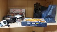Photo showing multiple kitchen items including a chef's knife block, waffle maker, kitchen timer, and a bag.