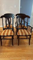Front view of 4 dining chairs, 2 with arms and 2 without, showing upholstery pattern and backrest design
