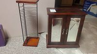 Jewelry box and CD holder rack placed beside each other on carpeted floor showing full view of both items.