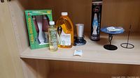 Wide shelf view showcasing citronella torch set box, bottle of citronella lamp oil, blue lava lamp with base, and black metal candle holders.