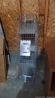Front view of the rectangular metal wire mesh live animal trap showing the spring-loaded door and handle on top.