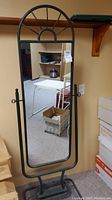 Front angle view of the full length mirror on a black metal swivel stand, featuring an arched top design.
