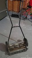Front angle view showing the push handle and blade reel mechanism of the mower.