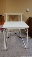 White metal wire rack with wood top and bed table in front