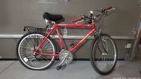 Side view of red Raleigh Portage bike with knobby tires and rear rack, showing the entire bike profile.