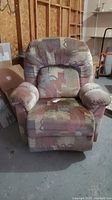 Front view of fabric rocker recliner chair showing padded armrests, cushioned seat and backrest with patterned upholstery.