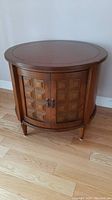 Front view of round cabinet showing carved panel doors and metal handles