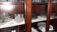 Six serving relish dishes, two bowls (one with chrome rim), four salt plates, and five luncheon plates on display shelf.