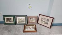 Five framed Trisha Romance prints arranged on the floor showing the variety of artwork and frame styles.