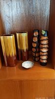 Overview of the full lot showing all 5 items on a wooden shelf: two pottery vases, two wooden vases, and one small dish.