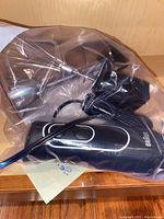 Braun immersion blender motorized hand unit, whisk attachment and power cord in plastic bag on wooden surface.