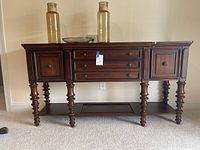 Full front view of dark wood buffet showing turned legs, multiple drawers, and cabinets.