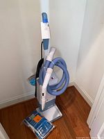 Full view of the Electrolux upright vacuum cleaner with attached hose and wand, set on hardwood floor.