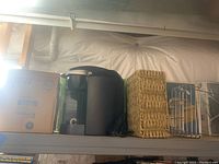 Ultrasonic cool mist humidifier box, fabric steamer box, and black Keurig coffee maker on shelf with basket and metal rack
