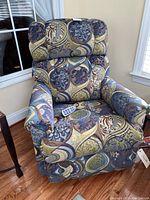 Front view of blue, green and brown printed motorized recliner with remote on seat.