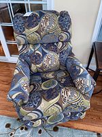 Front view of upholstered swivel rocker recliner showing blue, green and brown patterned fabric with padded arms and back