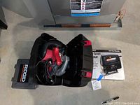 Black & Decker jig saw inside black plastic carry case with red latches alongside user manual and a small extra blade.