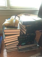 Stack of various books including The Harvard Classics set with dark covers and gold embossed details.