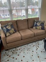 Full front view of tan microfiber sofa with two throw pillows