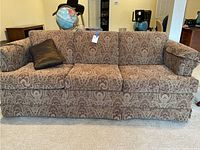 Front view of paisley patterned sofa with three seat cushions and rolled arms