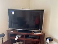 Front view of Sony TV on wooden stand, showing screen and built-in speakers along sides