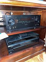 Pioneer Elite receiver, Sony device, and Denon CD player stacked on a wooden shelf.