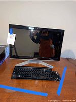 Toshiba all-in-one desktop computer on wooden desk with keyboard and wired mouse in front