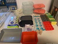 Full view of all kitchen accessories available in the lot on display including containers, ice trays, sponges, and holders.