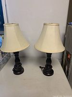 Pair of matching table lamps with cream fabric shades and dark espresso color bases approximately 19 inches tall.